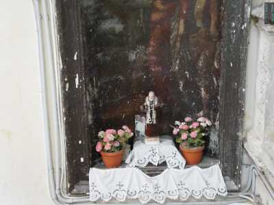 Al di sotto una statuetta in ceramica di San Pio circondata da vasetti con fiorellini rosa e bianchi � invece testimonianza di un culto tutto contemporaneo